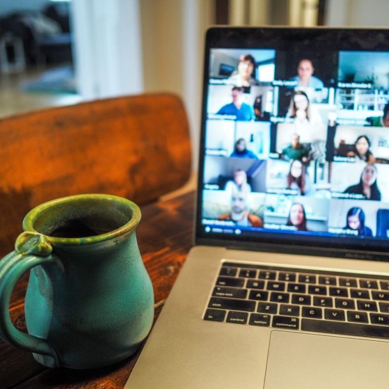 Online Business English Training – communicate effectively in virtual meetings. Laptop with a video conference on screen and a coffee mug on a wooden desk — symbolizing online English training and remote communication.